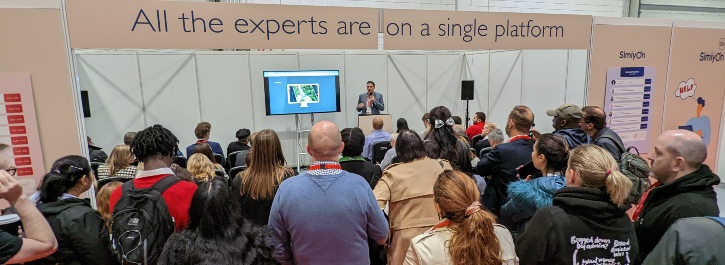 Will Roberts speaking at The Business Show event 2022 in London with a crowd of people listening