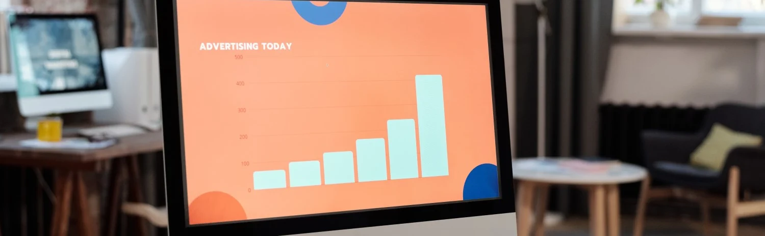 A computer monitor displays a bar graph with the title "Advertising Today" in an office setting.